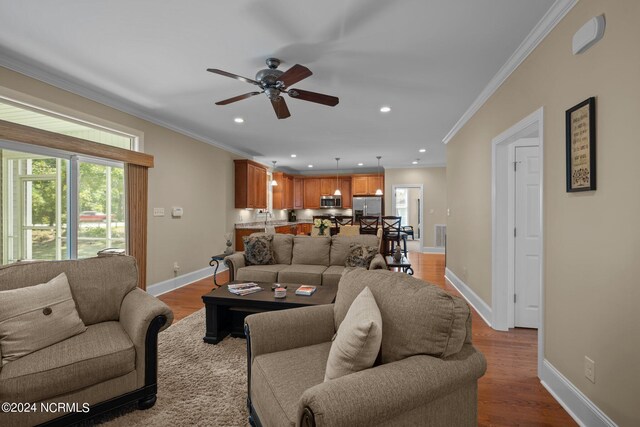 living room featuring crown molding, ceiling fan, and light hardwood / wood-style floors