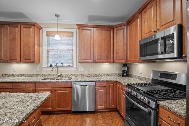 kitchen with light hardwood / wood-style flooring, light stone countertops, stainless steel appliances, sink, and ornamental molding