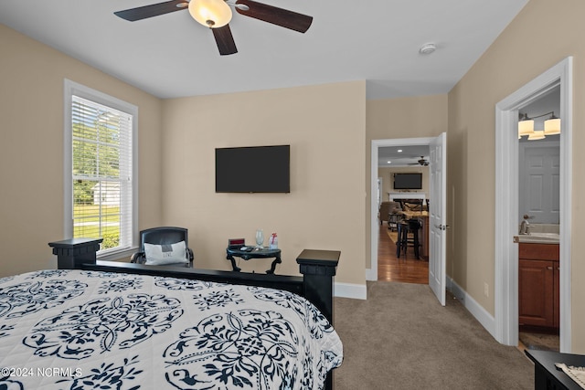 carpeted bedroom featuring a ceiling fan, connected bathroom, and baseboards