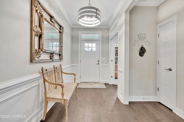 entryway with a chandelier, ornamental molding, and wood-type flooring