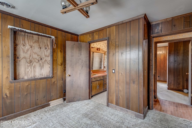 bedroom with light colored carpet, ensuite bath, and wood walls