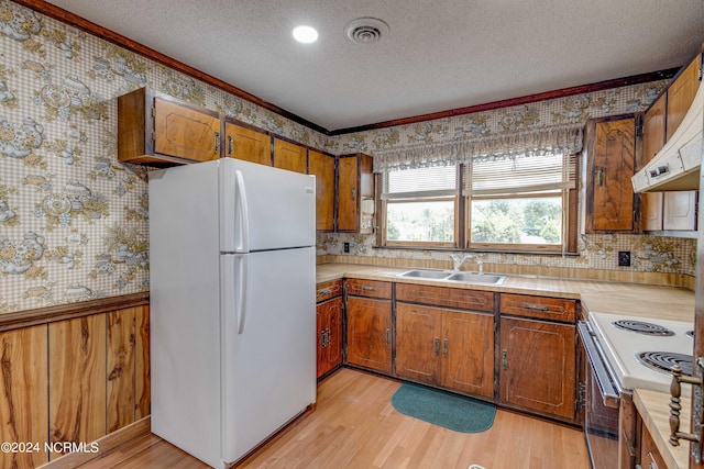 kitchen with light hardwood / wood-style floors, a textured ceiling, white appliances, and ornamental molding