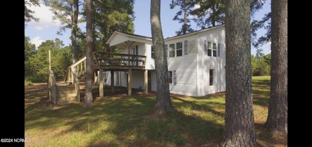 rear view of house featuring a lawn and a deck