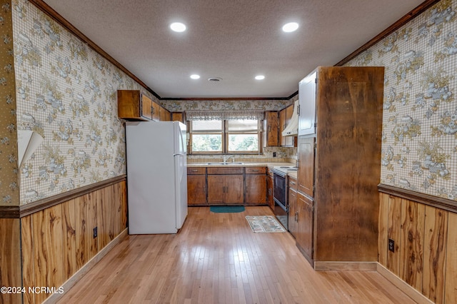 kitchen featuring light wood-type flooring, wood walls, white refrigerator, and black electric range oven