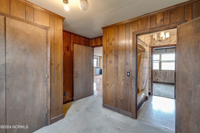 hall featuring light colored carpet, wooden walls, and crown molding