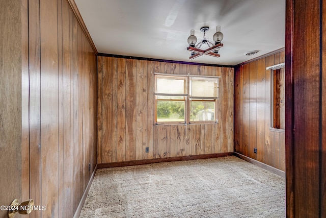 carpeted spare room featuring wood walls