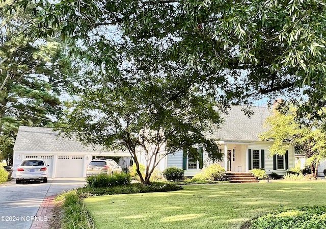 view of front of house with concrete driveway, a front lawn, and a shingled roof