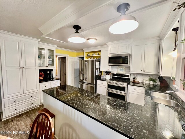 kitchen featuring backsplash, appliances with stainless steel finishes, white cabinets, and a sink