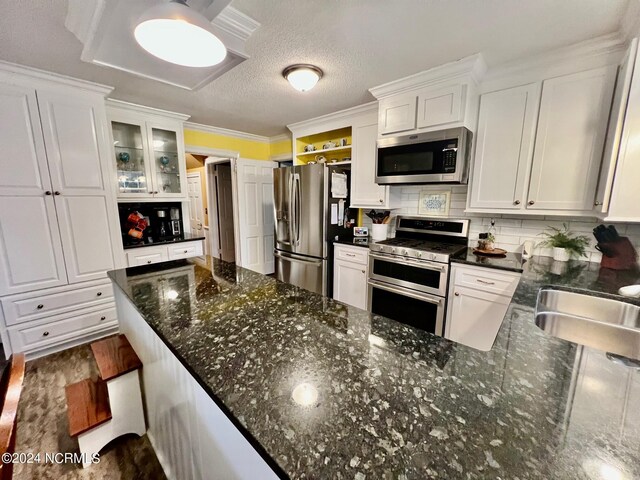 kitchen featuring decorative backsplash, white cabinets, appliances with stainless steel finishes, open shelves, and a sink