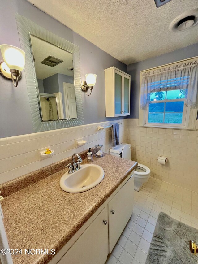 full bath with a stall shower, toilet, tile patterned floors, a textured ceiling, and vanity