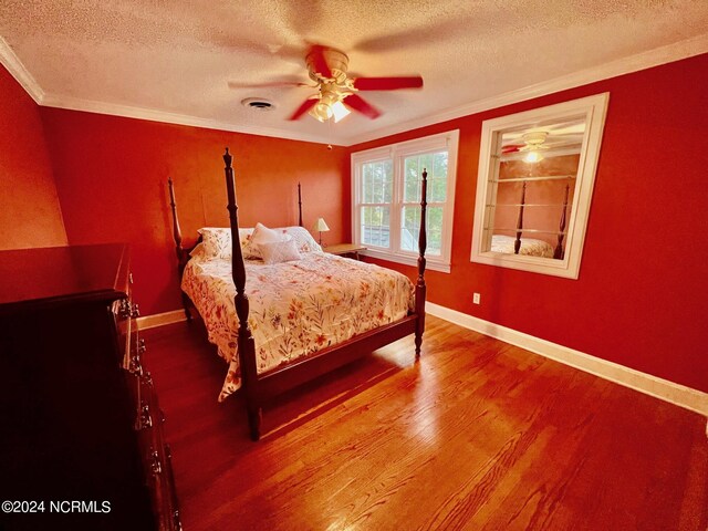 bedroom with visible vents, ornamental molding, a textured ceiling, wood finished floors, and baseboards