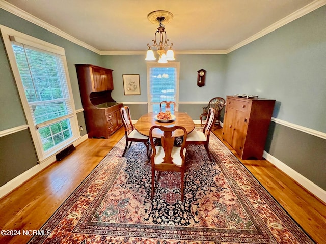 dining space with baseboards, ornamental molding, light wood-style flooring, and an inviting chandelier