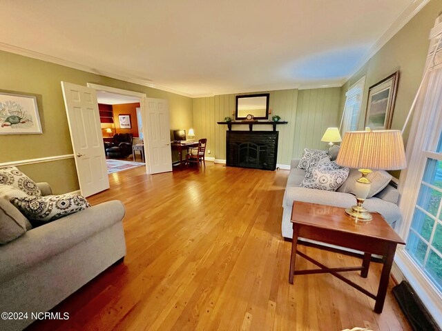 living room featuring crown molding, a fireplace, baseboards, and wood finished floors