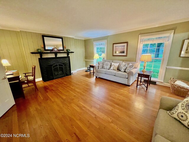 living area with a fireplace, ornamental molding, and hardwood / wood-style floors