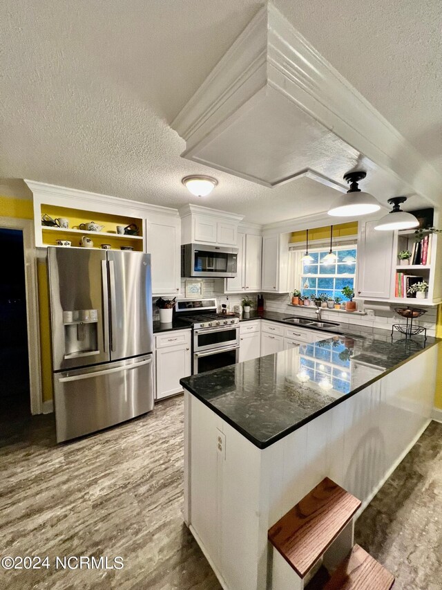 kitchen featuring open shelves, appliances with stainless steel finishes, white cabinetry, a sink, and a peninsula