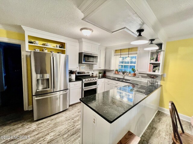 kitchen with appliances with stainless steel finishes, white cabinets, a peninsula, and open shelves