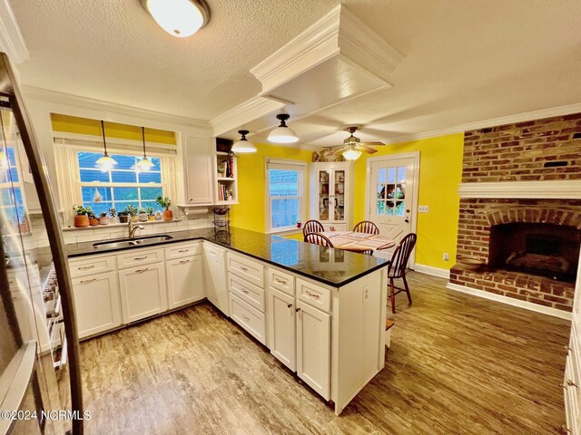 kitchen with dark countertops, light wood finished floors, a peninsula, and a sink