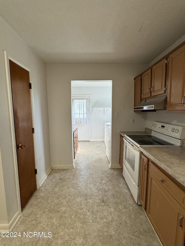 kitchen with under cabinet range hood, electric range, baseboards, and a textured ceiling