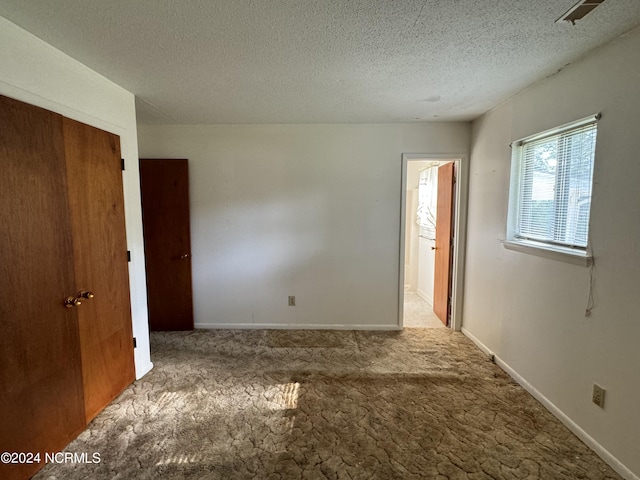 spare room with a textured ceiling, carpet flooring, and baseboards