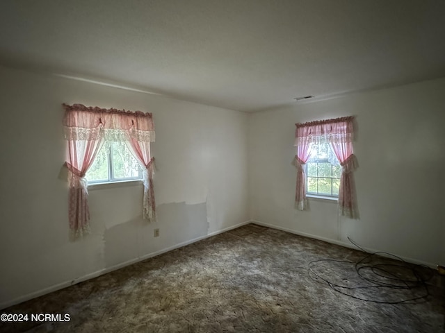 spare room featuring carpet, visible vents, and baseboards