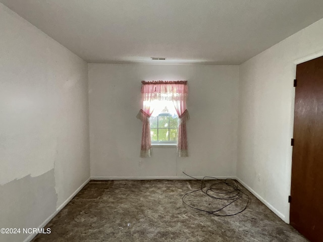 carpeted spare room featuring visible vents and baseboards