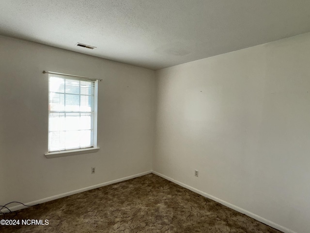 carpeted empty room featuring baseboards, visible vents, and a textured ceiling