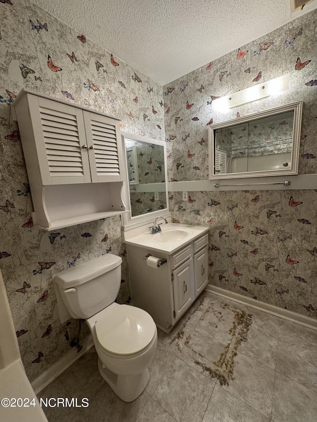 bathroom featuring a textured ceiling, toilet, vanity, baseboards, and wallpapered walls