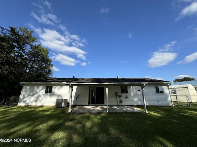 rear view of property featuring central AC unit, a lawn, and a patio area