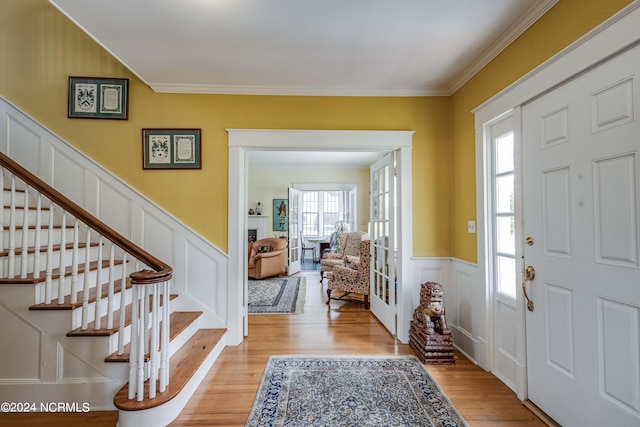 foyer entrance with light wood-type flooring, a wealth of natural light, and crown molding