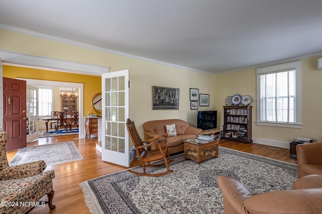 living room with crown molding, french doors, and light wood-type flooring