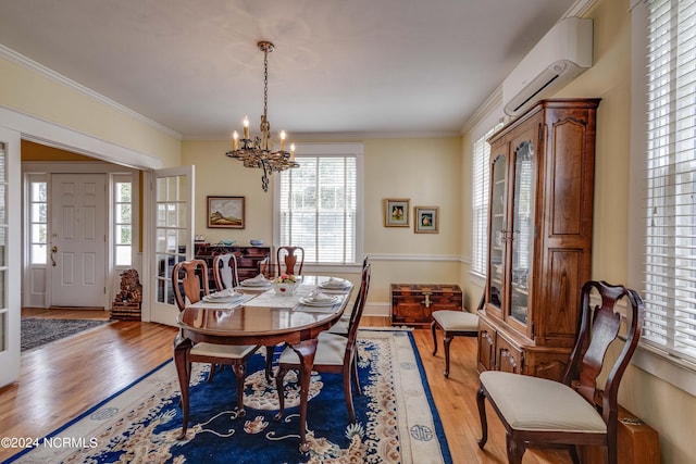 dining area with light wood-style flooring, a notable chandelier, baseboards, ornamental molding, and a wall mounted AC