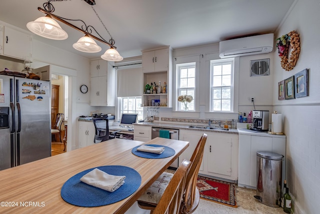 kitchen with white cabinets, a wall unit AC, appliances with stainless steel finishes, decorative light fixtures, and light countertops