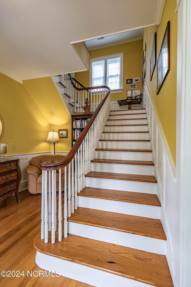 stairs featuring crown molding and wood finished floors