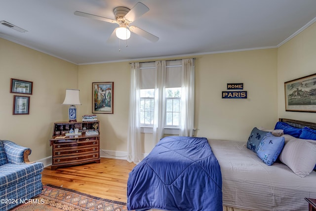 bedroom featuring visible vents, ornamental molding, ceiling fan, wood finished floors, and baseboards