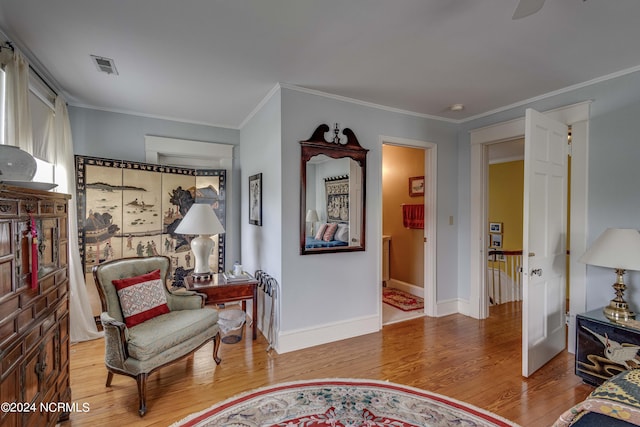 sitting room featuring crown molding and light hardwood / wood-style flooring