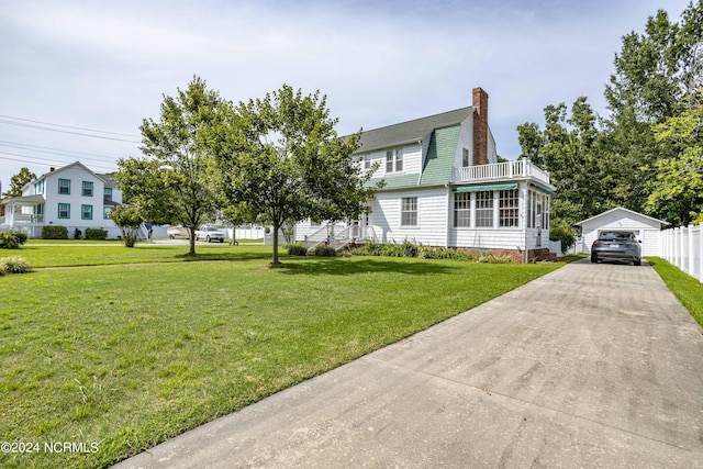 exterior space featuring a garage, a gambrel roof, a balcony, a chimney, and a front yard