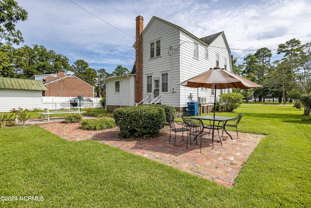 rear view of house featuring a yard, a patio, and fence