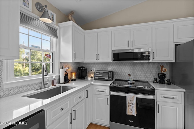 kitchen featuring appliances with stainless steel finishes, sink, tasteful backsplash, and lofted ceiling