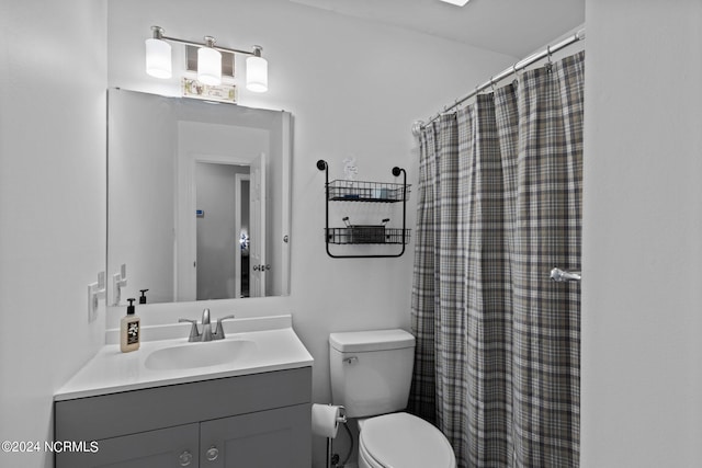 bathroom featuring toilet, vanity, and a shower with curtain