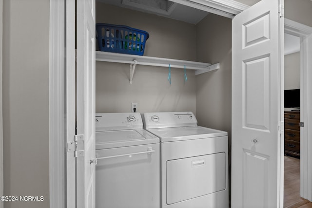 clothes washing area with washing machine and dryer and light wood-type flooring