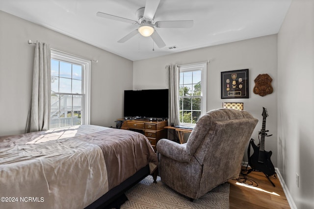 bedroom with ceiling fan, multiple windows, and hardwood / wood-style flooring