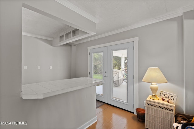 interior space featuring ornamental molding, light wood-type flooring, french doors, tile countertops, and a textured ceiling