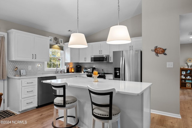 kitchen featuring appliances with stainless steel finishes, a center island, light hardwood / wood-style floors, and tasteful backsplash