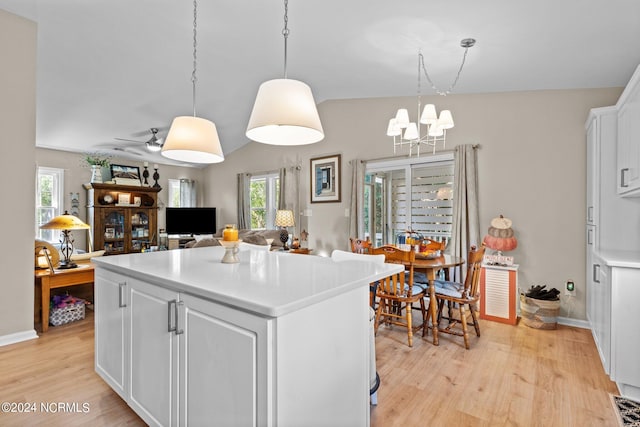 kitchen with a center island, light hardwood / wood-style flooring, ceiling fan with notable chandelier, white cabinetry, and pendant lighting