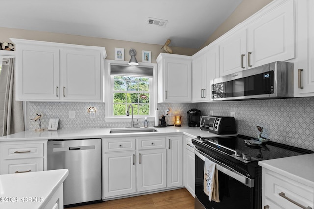 kitchen featuring sink, appliances with stainless steel finishes, light hardwood / wood-style flooring, decorative backsplash, and vaulted ceiling