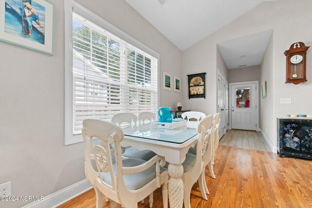 dining space with light hardwood / wood-style flooring, a wealth of natural light, and lofted ceiling