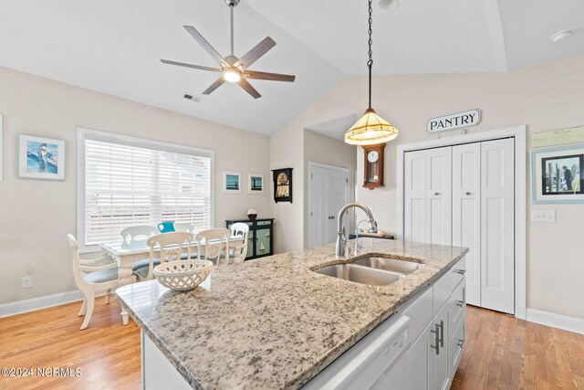 kitchen with a kitchen island with sink, white cabinets, light hardwood / wood-style flooring, vaulted ceiling, and decorative light fixtures