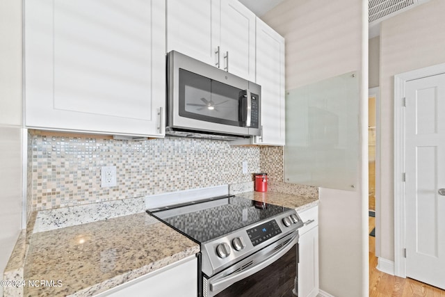 kitchen with stainless steel appliances, light stone counters, decorative backsplash, and white cabinets