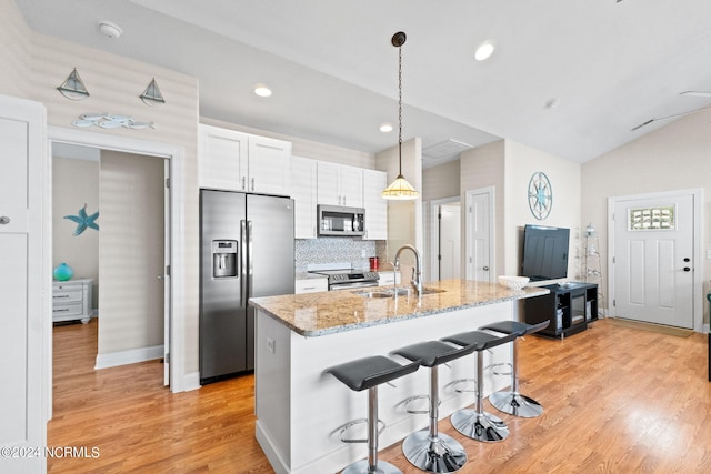 kitchen featuring light stone countertops, white cabinetry, appliances with stainless steel finishes, and light hardwood / wood-style flooring