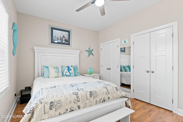 bedroom with baseboards, two closets, light wood-style flooring, and a ceiling fan